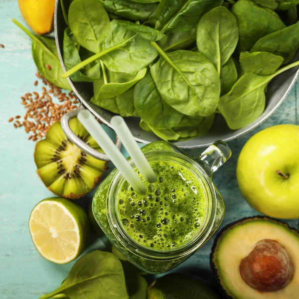 Healthy green smoothie and ingredients on blue background — Stock Photo, Image