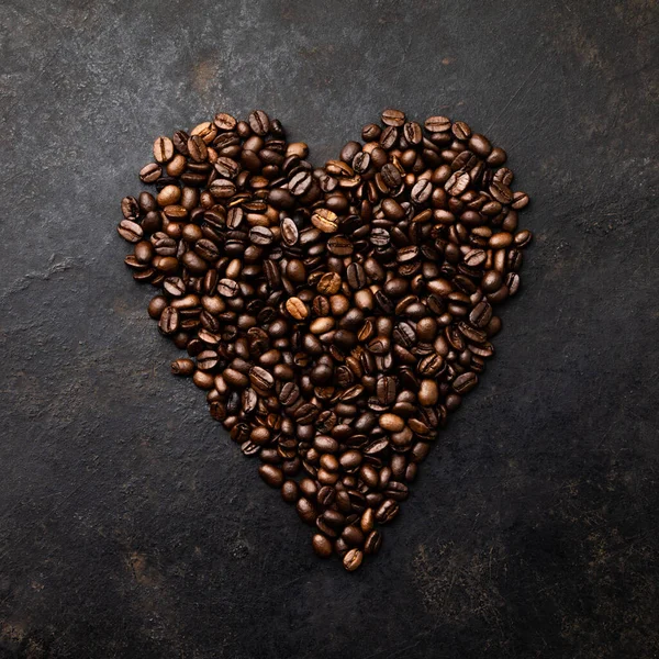 Grãos de café em forma de coração no fundo rústico escuro — Fotografia de Stock