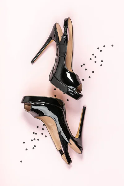 Zapatos negros de tacón alto para mujer y confeti negro sobre fondo rosa. Piso laico, vista superior de moda belleza femenina fondo. — Foto de Stock