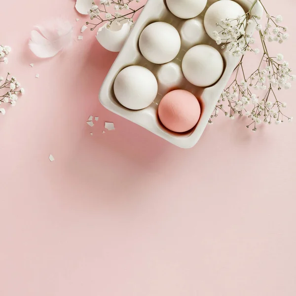 Ovos de Páscoa em suporte de cerâmica branca e flores em fundo rosa — Fotografia de Stock