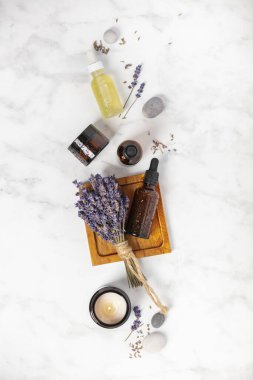 Beyaz mermer zemin üzerinde lavanta çiçekleri ve doğal kozmetik ile düz bileşim yatıyordu