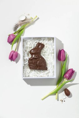 Paskalya kompozisyonu Pembe laleler ve çikolata tavşanlı beyaz arka planda hediye paketi