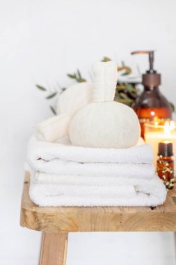 Kokulu mumlar, vücut losyonu, bitkisel toplar, spa havluları ve ahşap bankta narin çiçekler.