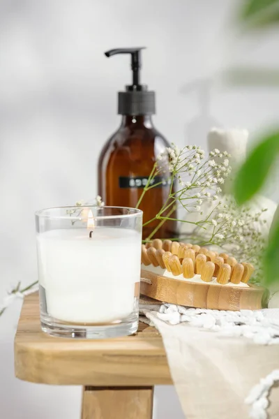 Λευκό αρωματικό κερί, λοσιόν σώματος, βούρτσα μασάζ κατά της κυτταρίτιδας, φυτικές μπάλες και ντελικάτα λουλούδια σε ξύλινο πάγκο Εικόνα Αρχείου