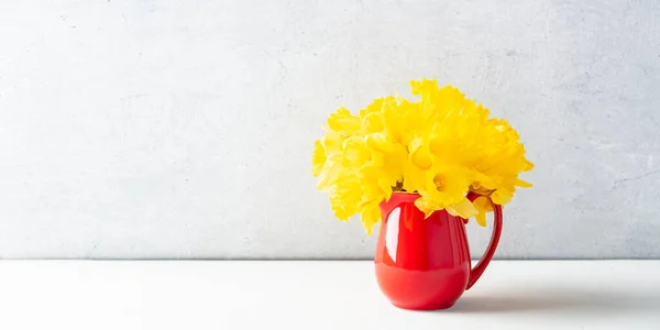 Buquê de narcisos amarelos em um jarro vermelho na parte superior da mesa, decoração home, interior — Fotografia de Stock