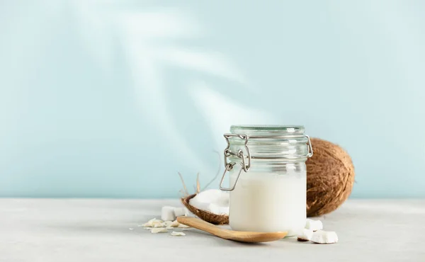 Kokosöl im Glas mit frischer Kokosnuss und tropischem Blattschatten, Kosmetik- und Lebensmittelzutat im Spa — Stockfoto