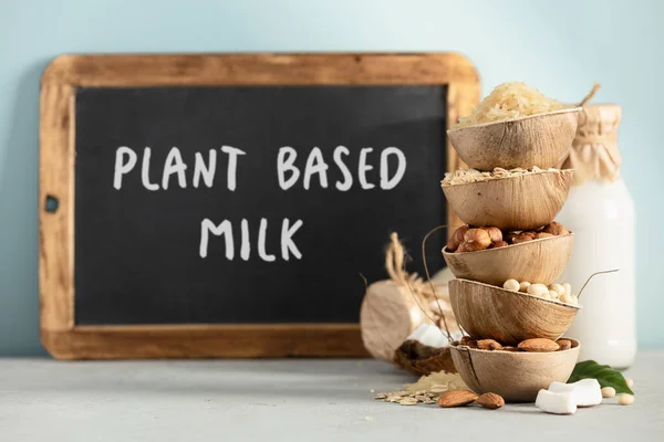 Rijst, haver, amandel, hazelnoot en sojabonen in natuurlijke palmblad kommen en melkflessen op tafel, Ingrediënten voor het maken van zuivelvrije melk vervangende dranken — Stockfoto