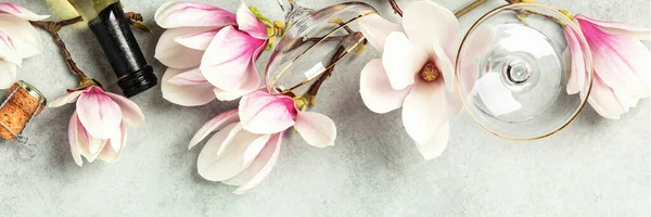 Mooie platte lag met lente magnolia bloemen, wijn en glazen op grijze stenen achtergrond — Stockfoto