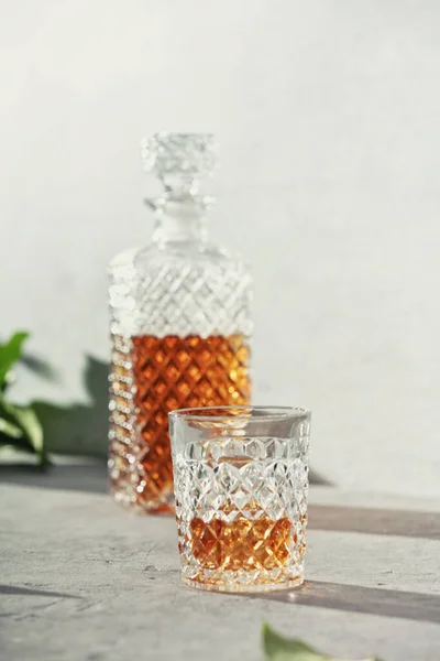 Glass of whiskey with ice cubes and carafe close up — Stock Photo, Image