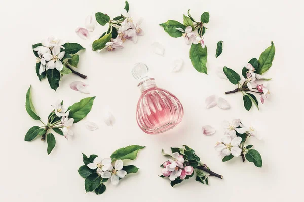 Schöne Parfümflaschen und Frühlingsblumen auf weißem Hintergrund — Stockfoto