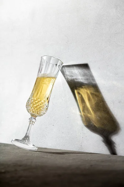 Bicchiere Champagne e lunga ombra di vetro contro muro di cemento — Foto Stock