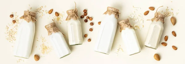 Milch auf pflanzlicher Basis in Flaschen und Zutaten auf hellem Hintergrund. Alternativer laktosefreier Milchersatz, flach liegend — Stockfoto