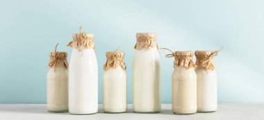 Süt bitkisi olmayan vegan sütü mavi arka plandaki şişelerde. Alternatif laktozsuz süt ikamesi, afiş
