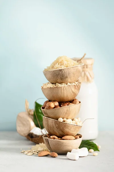 Rice, oat, almond, hazelnut and soy beans in natural palm leaf bowls and milk bottles on the table, Ingredients for making Dairy free milk substitute drinks — Stock Photo, Image