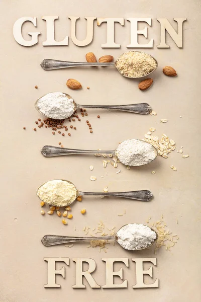 Metal spoons of various gluten free flour almond flour, oatmeal flour, buckwheat flour, rice flour, corn flour and gluten free lettering made of wooden letters, flat lay, top view — Stock Photo, Image