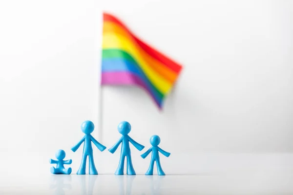 带孩子的同性恋夫妇的塑像和浅灰背景的LGBT彩虹旗 — 图库照片