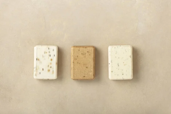 Tre saponette naturali - lavanda, cotone, patchouli - su fondo di pietra naturale, posa piatta — Foto Stock
