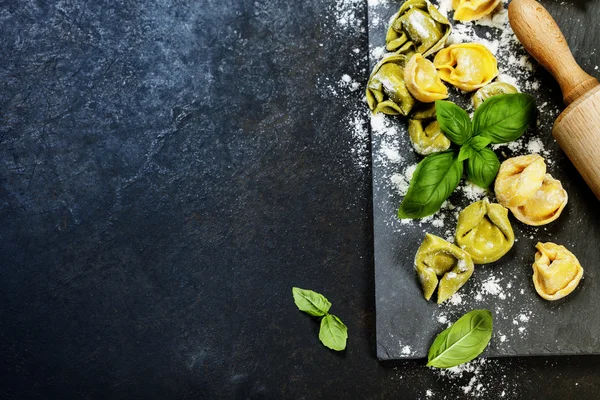 Homemade raw Italian tortellini and basil leaves