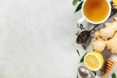 Taze zencefil, limon, bal ve hafif taştan bir zemin üzerinde gevşek çay yaprakları olan bitki çayının üst görüntüsü, sağlık ve sağlık teması için ideal..