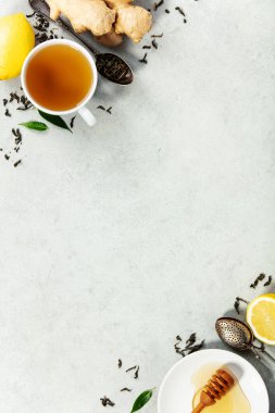 Hafif bir yüzey üzerinde zencefil, limon, bal ve gevşek çay yapraklarıyla sade bir bitki çayı seti, sağlık, sağlık ve yaşam tarzı temaları için ideal..