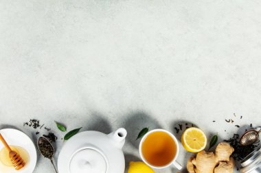 Tarafsız bir yüzeyde zencefil kökü, limon ve gevşek çay yapraklarıyla bir fincan bitki çayı. Sağlık, sağlık ve besinle ilgili kavramlar için mükemmel..