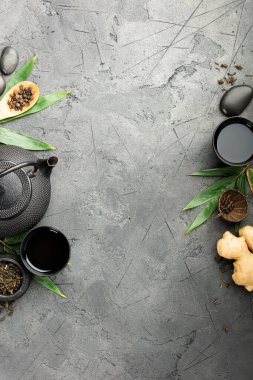Geleneksel çaydanlık, çay fincanları, zencefil ve yeşil yapraklar.