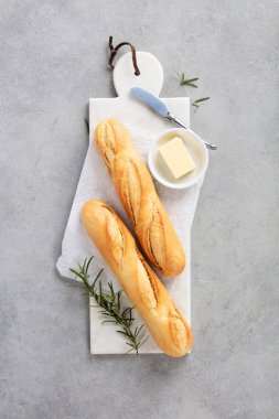 İki altın baget mermer kesim tahtasının üzerindeki parşömenin üzerinde duruyor, hafif taşlı arka planda şekillendirilmiş.