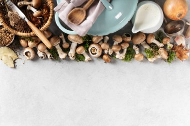 Sarımsak, soğan, süt, otlar ve gri arka planda kırsal mutfak aletleriyle taze mantar. Tarladan sofraya aşçılık ya da sonbahar tarifi konsepti.