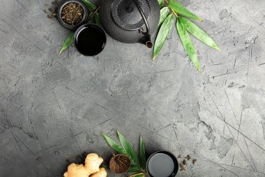 Geleneksel siyah çaydanlık, çay fincanları, zencefil ve yeşil yapraklar fotokopi alanı, menüler, spa ya da çay markaları için mükemmel olan koyu renkli taş yüzeyde..