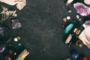 Kara desenli bir yüzey üzerinde gerekli yağ şişesi olan ham ve cilalanmış taşlar koleksiyonu meditasyon ve sağIık teması için mükemmel..