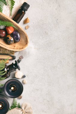 Gri arka planda kurumuş çiçekli iki kahverengi yağ şişesi, refah ve aromaterapi temaları için minimalist, doğal bir estetiği çağrıştırıyor. Model yap, boşluğu kopyala