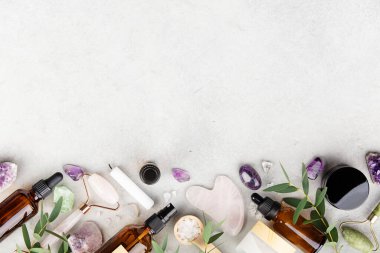 Kehribar cam şişeler, yeşim taşı ve gül kuvars yüz aletleri, ametist kristalleri, tuz ve okaliptüs yapraklarından oluşan düz bir bileşim.