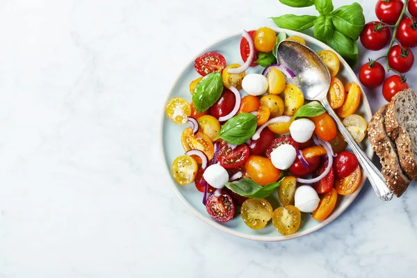 Tomates frescos con hojas de albahaca en un bol —  Fotos de Stock