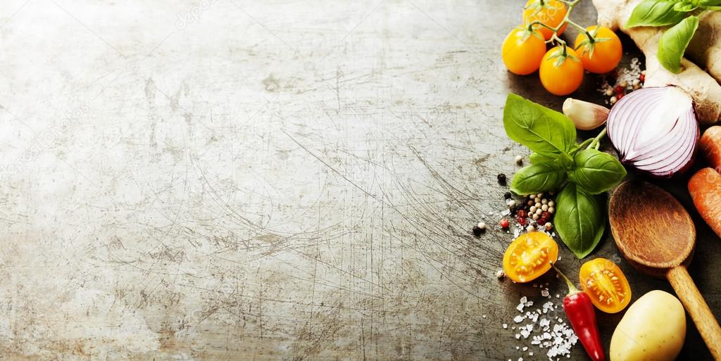 Wooden spoon and fresh organic vegetables on old background