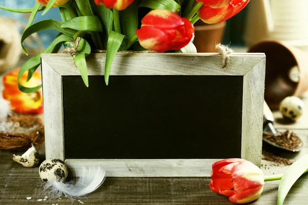 Hermoso ramo de tulipanes, huevos de Pascua y herramientas de jardín en madera — Foto de Stock