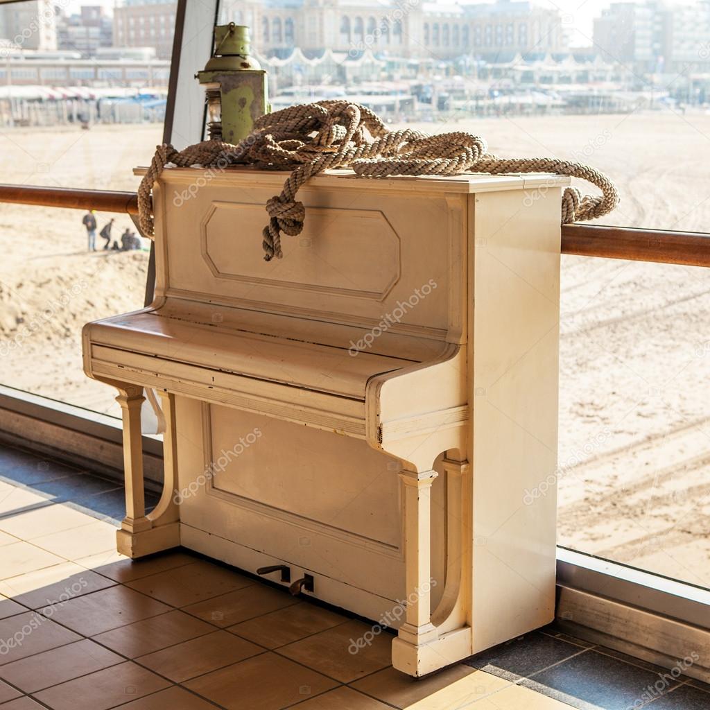 Old white piano on one pier of North Sea.