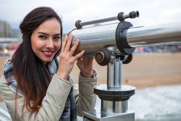 Beautiful young woman with magnificent hairs near telescope on pier in the Hague. — Stock Photo, Image