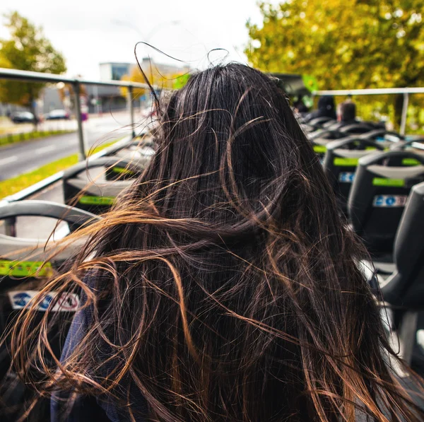 Young woman with long beautiful hairs soaring on wind sit back in open tour bus. — Stock Photo, Image