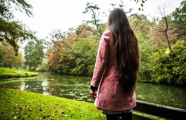 Attraente giovane donna con lunghi bei capelli vestiti cappotto rosa in posa all'aperto . — Foto Stock