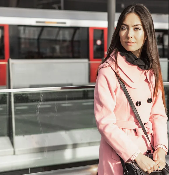 Retrato de mujer joven atractiva con largos y hermosos pelos vestidos de abrigo rosa en la estación de metro . —  Fotos de Stock