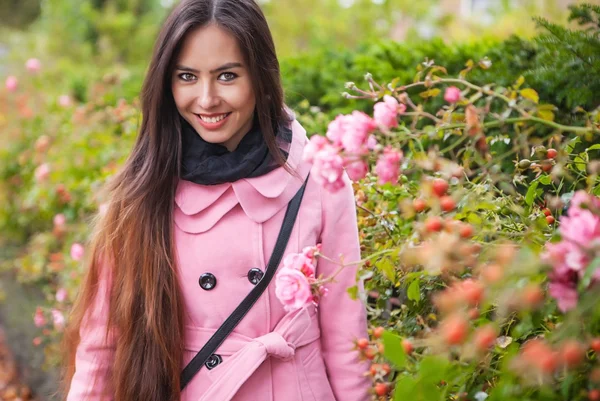 Atractiva mujer joven con largos y hermosos pelos vestido abrigo rosa posando al aire libre . —  Fotos de Stock