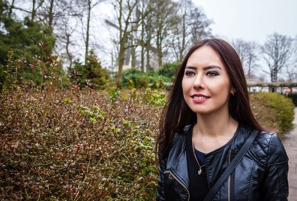 Attractive young friendly woman with long beautiful hairs posing in park.