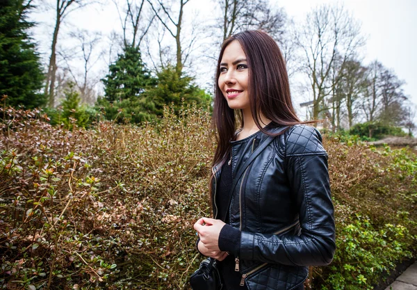 Attractive young friendly woman with long beautiful hairs posing in park. — Stock Photo, Image