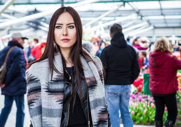 Attraktive junge Frau mit langen, schönen Haaren posiert im Blumengewächshaus des Keukenhofparks. — Stockfoto