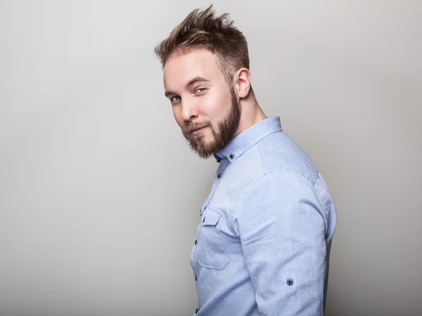 Retrato de jovem bonito homem amigável em camisa azul. Estúdio foto no fundo cinza claro . — Fotografia de Stock