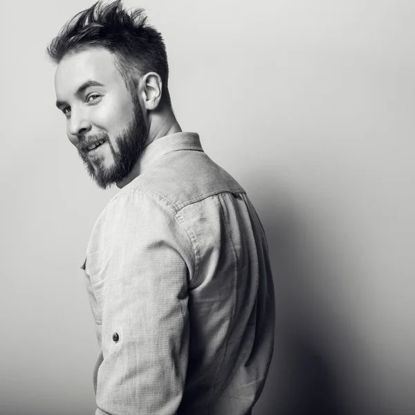 Retrato de un joven guapo y simpático hombre de camisa brillante. Foto de estudio blanco y negro sobre fondo gris claro . —  Fotos de Stock