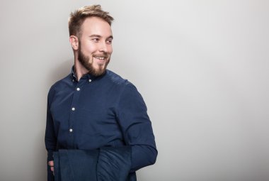 Koyu mavi klasik gömlek ve ceket omzunun üstünde zarif genç yakışıklı adam. Studio moda portre.