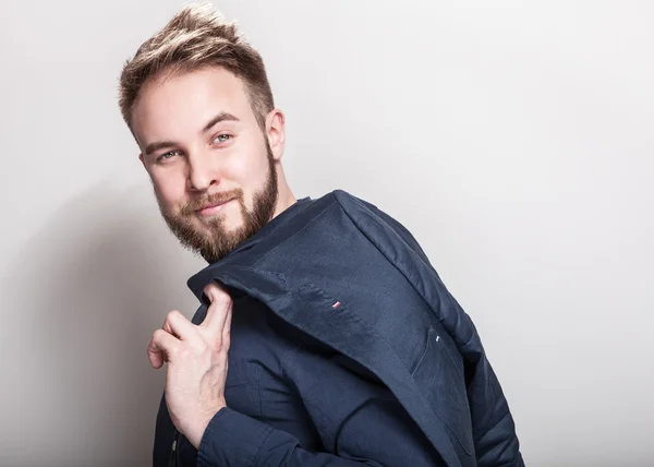 Elegant young handsome man in dark blue classic shirt and jacket on his shoulder. Studio fashion portrait. — Stock Photo, Image