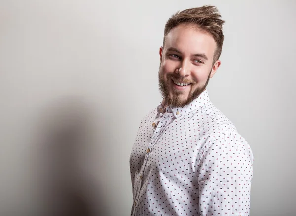 Porträt eines jungen, gut aussehenden positiven Mannes in weißem Hemd mit amüsantem Muster. — Stockfoto