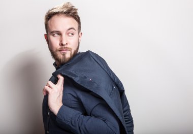 Koyu mavi klasik gömlek ve ceket omzunun üstünde zarif genç yakışıklı adam. Studio moda portre.